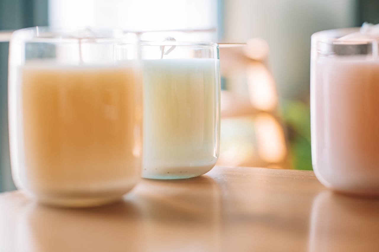 Close-up of aromatic candles in assorted colors on a wooden table, creating a calm ambiance.